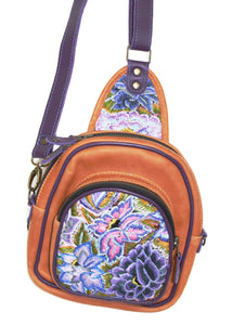 MoonLake Designs Blake Sling Over Backpack Bag in pear tan handcrafted leather with vibrant floral huipil in shades pink and purple featuring dark purple leather adjustable strap and multiple easy access pockets perfect for concerts or traveling
