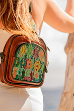 Load image into Gallery viewer, Woman wearing MoonLake Designs Blake sling over backpack bag made of handcrafted red brown leather and handwoven geometric huipil
