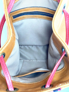 MoonLake Designs Maya bucket backpack inside view of pear leather, cream cloth interior, and zippered and open pockets